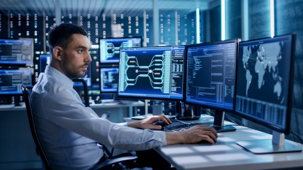 man infront of computer with three screens