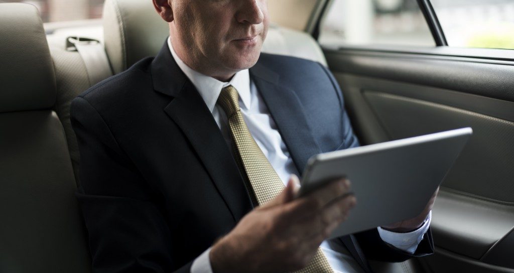 Businessman using his tablet in his car