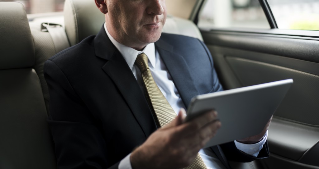 Businessman using his tablet in his car