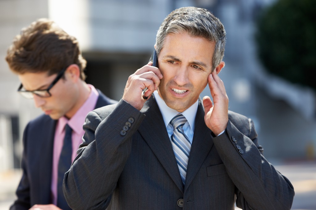 businessman on call covering his ears